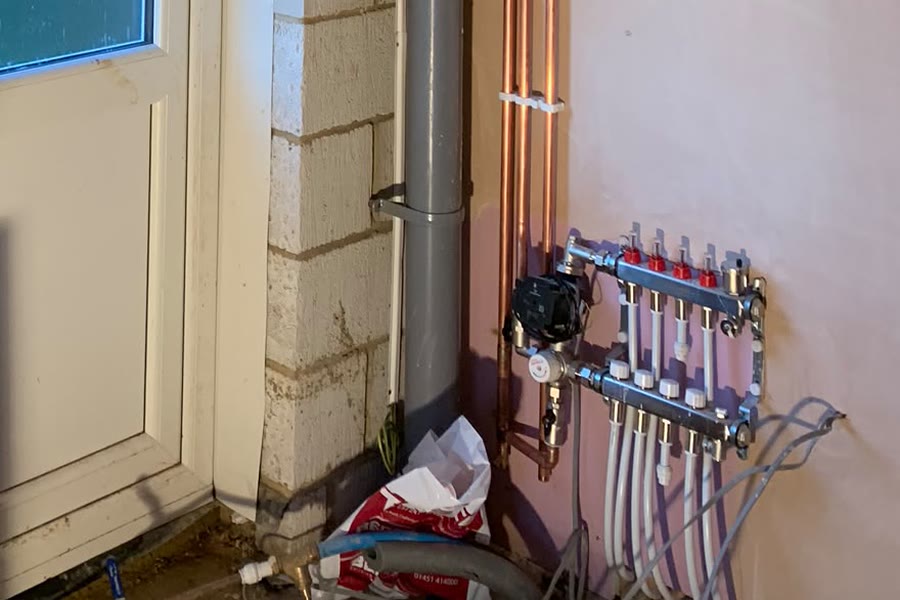 An underfloor heating manifold with pump and blending valve in a plant room
